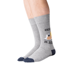 Lifestyle shot of a person wearing the 'Knish Me, I'm Jewish' socks. The socks are gray with a navy blue cuff and feature a knish graphic.