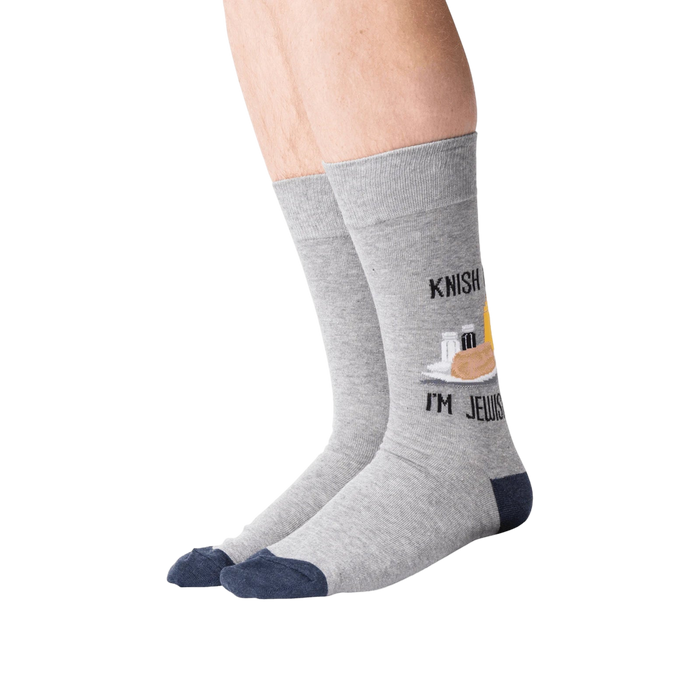 Lifestyle shot of a person wearing the 'Knish Me, I'm Jewish' socks. The socks are gray with a navy blue cuff and feature a knish graphic.