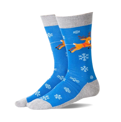Pair of blue non-skid slipper socks with flying brown reindeer, red harness, white snowflakes, and grey cuffs, heels, toes.