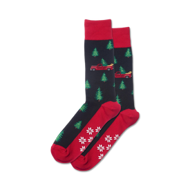 black crew socks with red pickup trucks hauling green christmas trees, red cuffs and toes with white snowflakes, non-skid grippers on red soles.   
