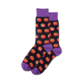 Pair of crew socks with a dark background and orange grinning pumpkin pattern. Purple cuffs.