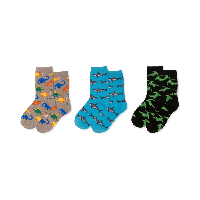 Three pairs of crew socks: one tan with colorful dinosaurs, one blue with grey sharks, and one black with green crocodiles. }}