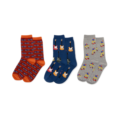 Three pairs of crew socks displayed side-by-side. Left: red-orange with blue cars. Middle: dark blue with colorful electric guitars. Right: light gray with skateboarding figures.