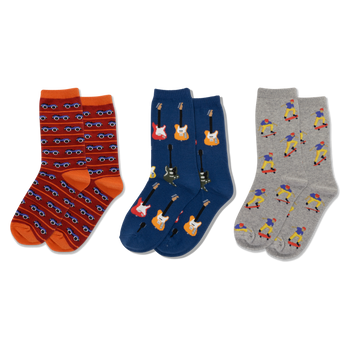 Three pairs of crew socks displayed side-by-side. Left: red-orange with blue cars. Middle: dark blue with colorful electric guitars. Right: light gray with skateboarding figures.