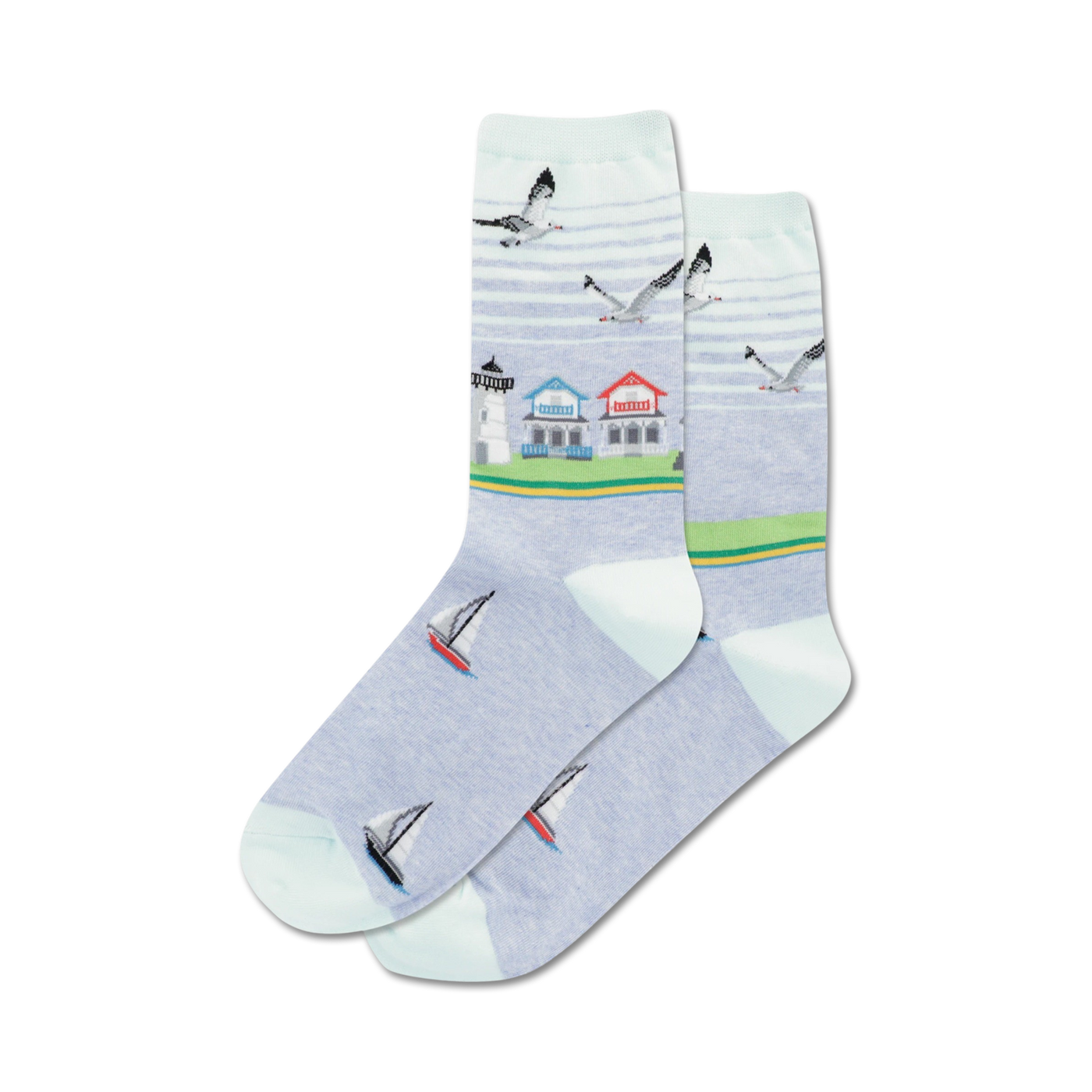 Pair of crew socks in light blue featuring a beach scene: lighthouse, houses, sailboats, and seagulls.