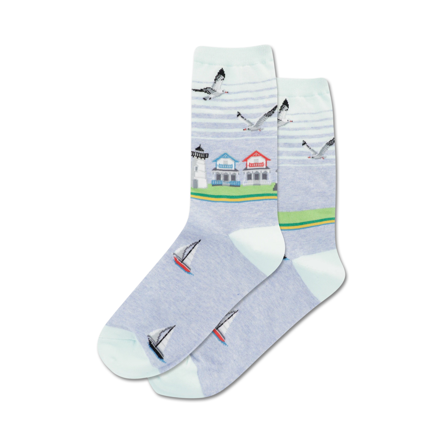 Pair of crew socks in light blue featuring a beach scene: lighthouse, houses, sailboats, and seagulls.