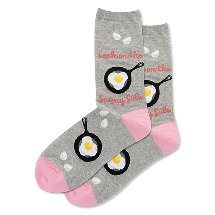 Pair of grey crew socks with black frying pans and fried eggs. Pink toes, white drop shapes, and 