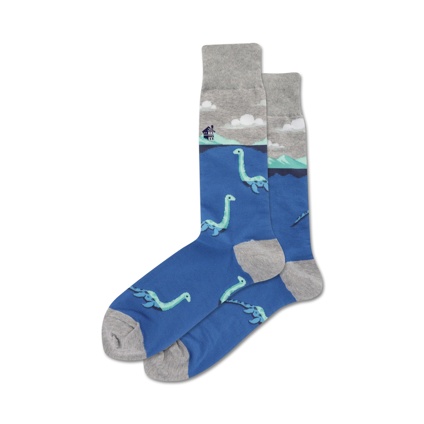 A pair of blue crew socks with a grey cuff. The socks feature a repeating pattern of light teal Loch Ness monsters swimming in the water, with a small house on a hill in the background.
