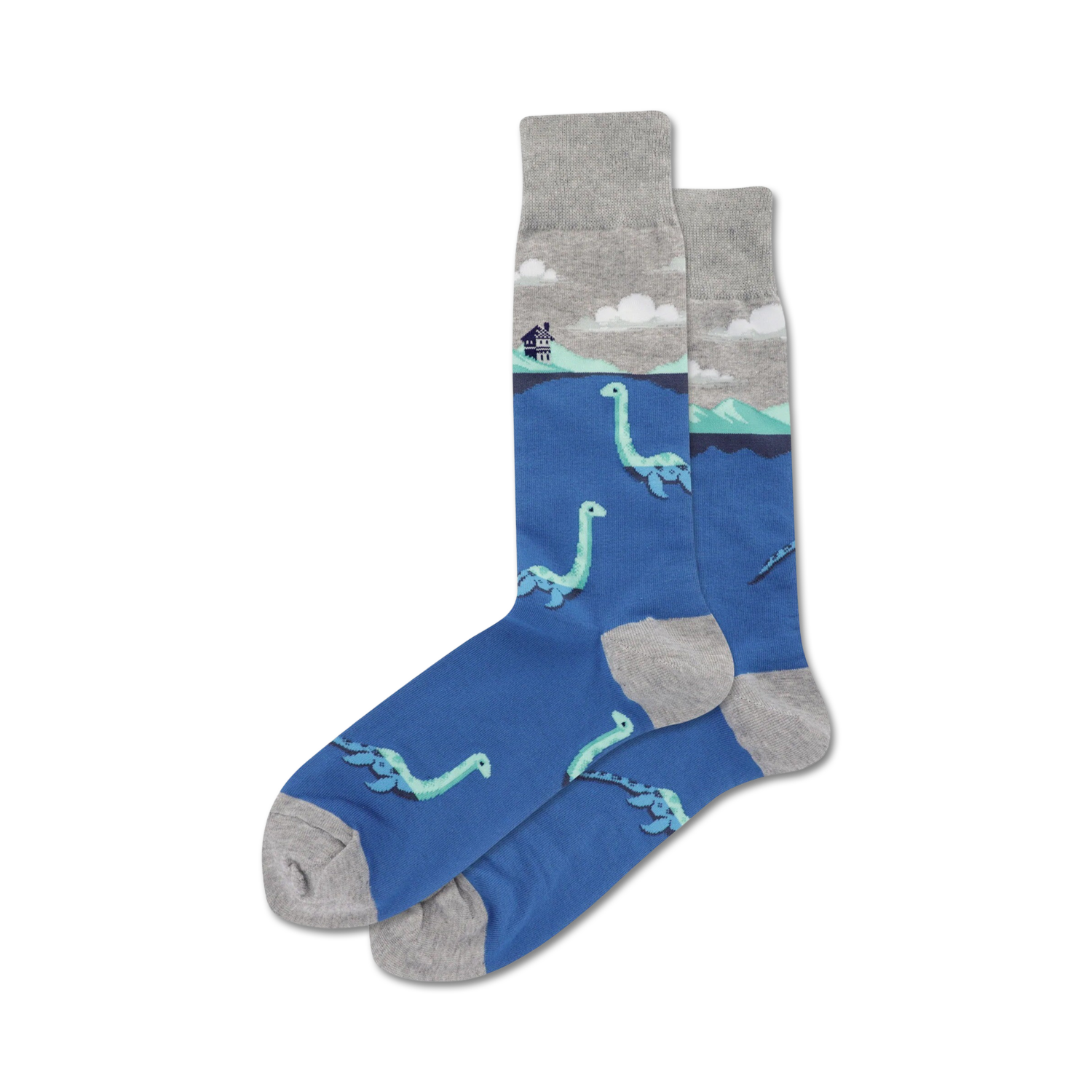 A pair of blue crew socks with a grey cuff. The socks feature a repeating pattern of light teal Loch Ness monsters swimming in the water, with a small house on a hill in the background.
