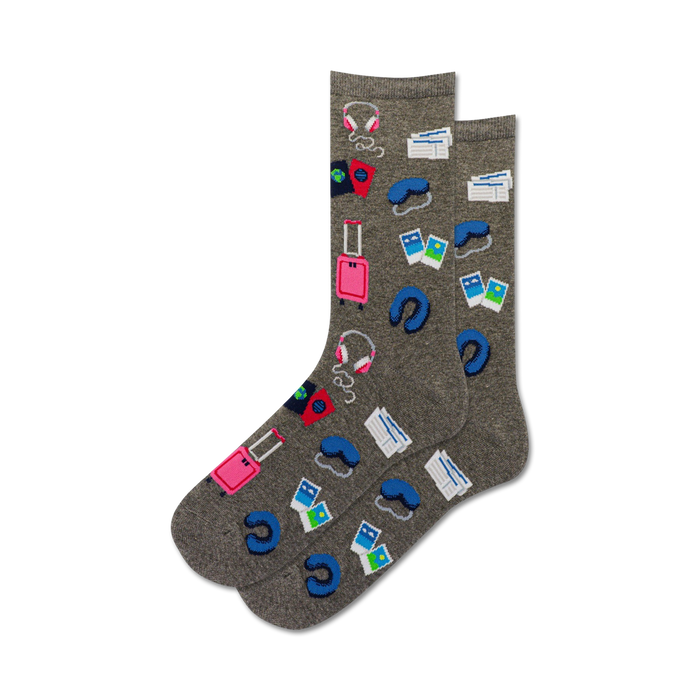 gray crew length novelty socks for women featuring pink luggage, blue headphones, airplane tickets, a neck pillow and a passport.  