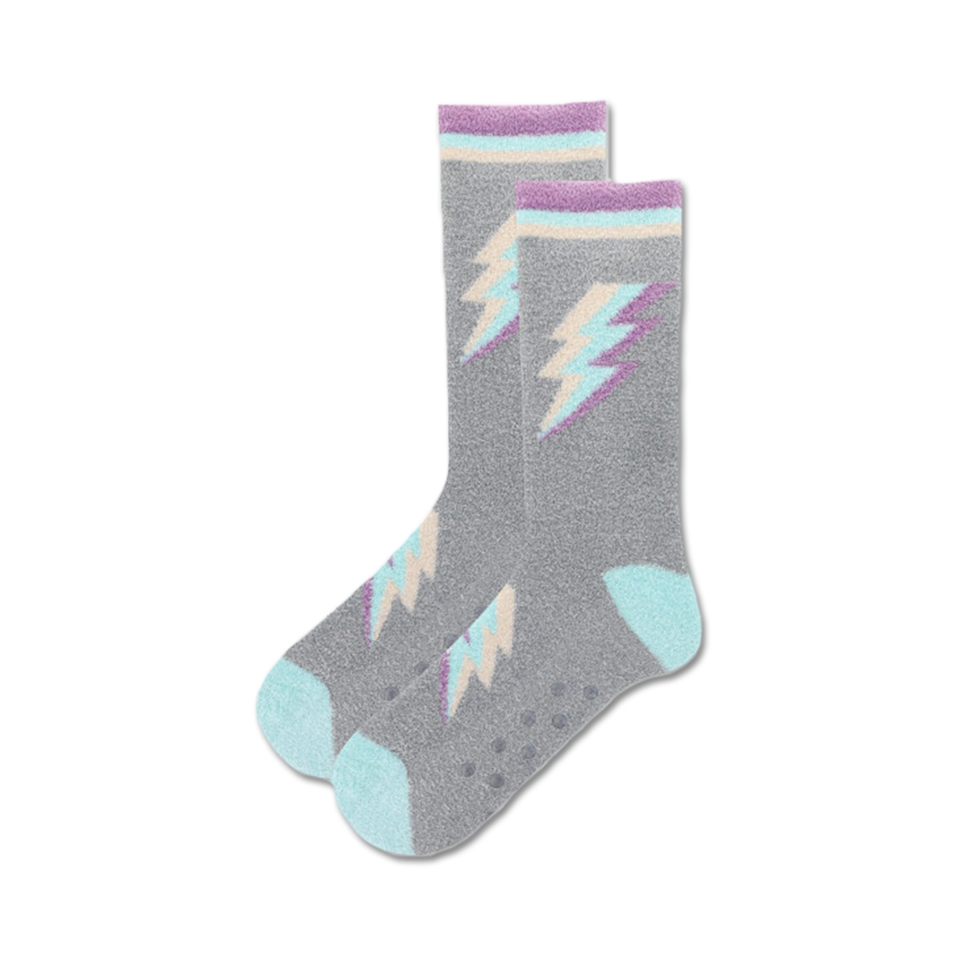 Lifestyle shot of gray fuzzy crew socks with pastel purple and teal lightning bolt designs. Non-skid grips on soles are visible.
