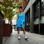 Lifestyle shot: woman in a blue dress wearing grey poppy floral socks and white loafers.