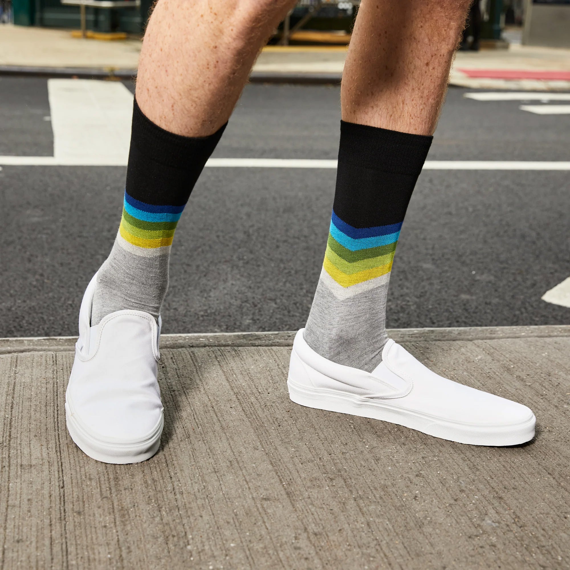 Lifestyle shot of a man wearing the chevron socks with white slip on shoes. [lf]