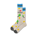 A close-up studio shot shows a pair of beige pickleball socks with teal stripes. The design includes paddles, balls, and the text 'I love Pickleball'.