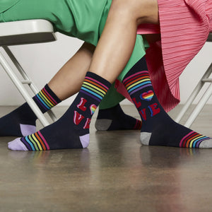 A pair of navy blue socks with rainbow stripes at the top and the word 