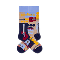 A pair of crew socks with a retro music theme. The socks feature illustrations of guitars, trumpets, and other instruments in shades of blue, red, yellow, and beige.