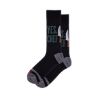 Pair of black crew socks featuring "YES, CHEF" in green text and silver chef knives. Grey heel, toe, and arch details.