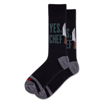 Pair of black crew socks featuring "YES, CHEF" in green text and silver chef knives. Grey heel, toe, and arch details.