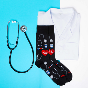 Medical socks laid over a folded white lab coat next to a real stethoscope on a split light blue and white background.