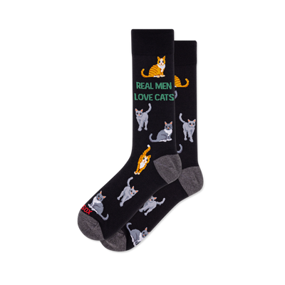Pair of black crew socks with grey heel and toe. Features green text 'REAL MEN LOVE CATS' and an all-over pattern of grey and orange tabby cats.