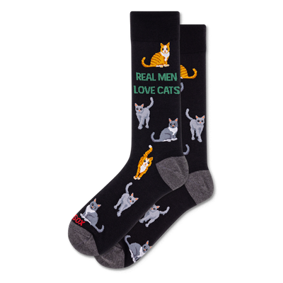 Pair of black crew socks with grey heel and toe. Features green text 'REAL MEN LOVE CATS' and an all-over pattern of grey and orange tabby cats.