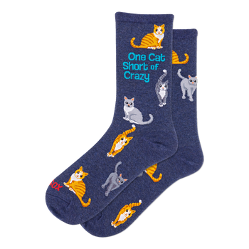 Two navy blue crew socks with a pattern of orange tabby and grey cats in various poses. One sock features text: 'One Cat Short of Crazy'.