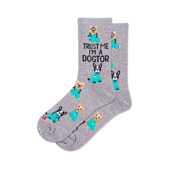 Pair of grey crew socks with a repeating pattern of cartoon dogs in teal medical scrubs, some with stethoscopes. Text reads "TRUST ME I'M A DOGTOR".