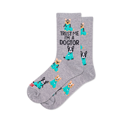 Pair of grey crew socks with a repeating pattern of cartoon dogs in teal medical scrubs, some with stethoscopes. Text reads "TRUST ME I'M A DOGTOR".