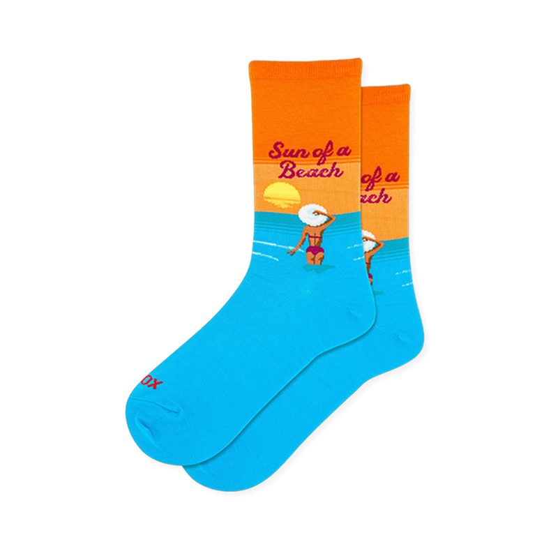 Bright blue and orange crew socks showing a woman in a pink bikini and white hat wading in the water below a setting sun.