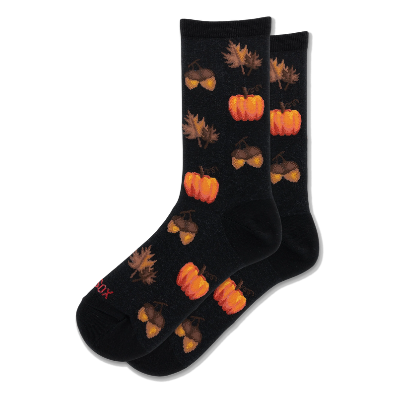 Black crew socks with a repeating pattern of bright orange pumpkins and brown acorns alongside scattered autumn leaves.