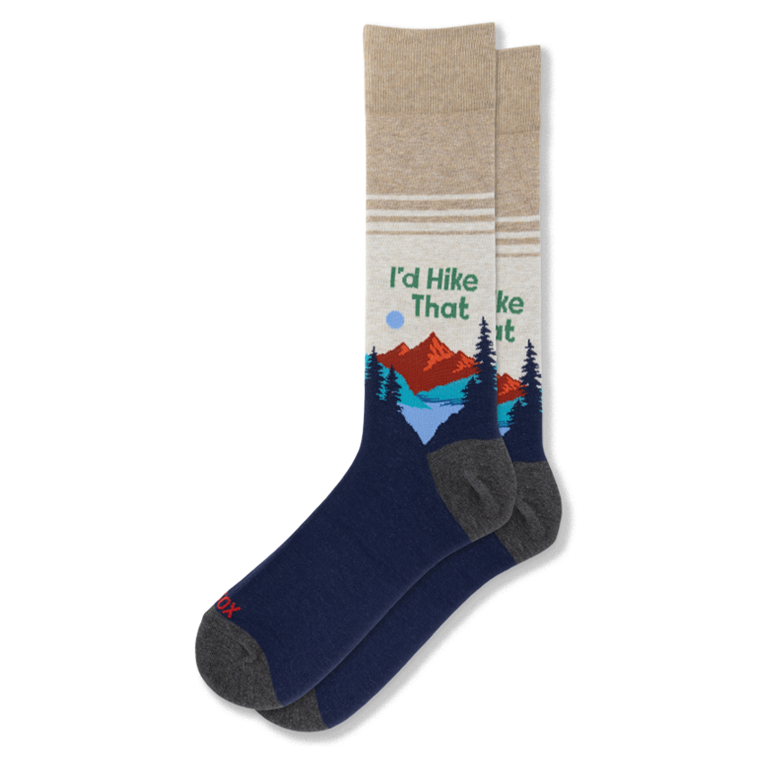 Crew socks featuring a beige upper, navy blue foot, mountains, pine trees, and green text reading I'd Hike That.