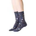 Lifestyle shot of woman's legs wearing navy blue crew socks with dogs on them.