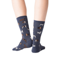 Back view lifestyle shot of woman's legs wearing navy blue crew socks with dogs on them.