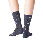 Back view lifestyle shot of woman's legs wearing navy blue crew socks with dogs on them.