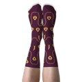 Person wearing deep burgundy crew socks with golden chains, daggers, and flaming hearts against a solid black background.