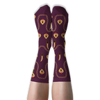 Person wearing deep burgundy crew socks with golden chains, daggers, and flaming hearts against a solid black background.