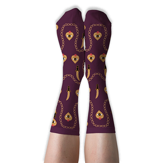 Person wearing deep burgundy crew socks with golden chains, daggers, and flaming hearts against a solid black background.