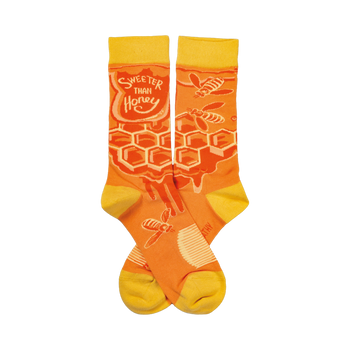 Crew socks in orange and yellow. Feature a honeycomb pattern, dripping honey, and bees. Text reads 'Sweeter Than Honey'.
