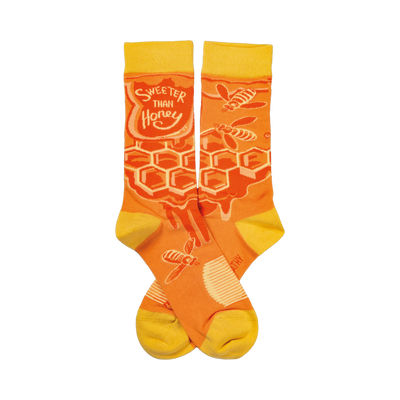 Crew socks in orange and yellow. Feature a honeycomb pattern, dripping honey, and bees. Text reads 'Sweeter Than Honey'.