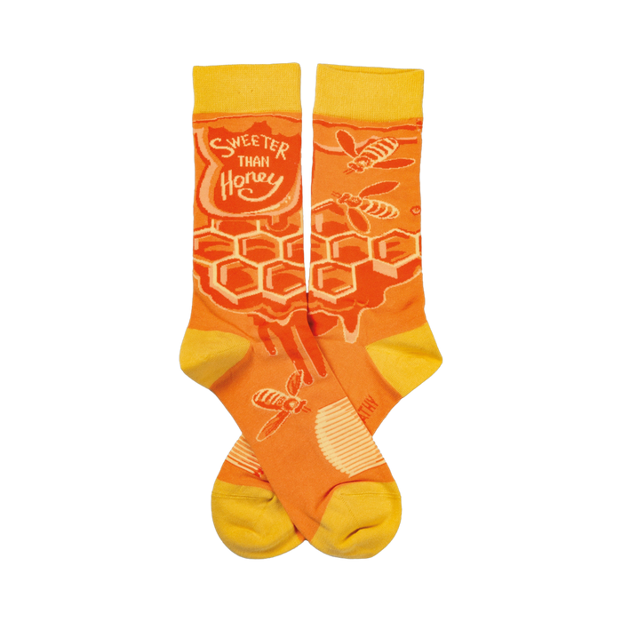 Crew socks in orange and yellow. Feature a honeycomb pattern, dripping honey, and bees. Text reads 'Sweeter Than Honey'. }}