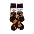 Pair of brown crew socks with a tan book stack design and a white label reading 'These Are My Reading Socks' and 'Leave Me Alone'.