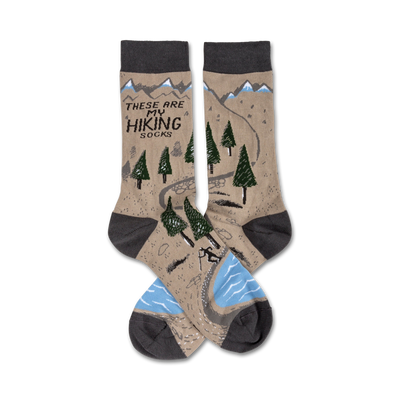 brown crew socks with hiking trail graphic including mountains, trees, river and hiker. text 'these are my hiking socks' displayed on top of socks. for men and women.  