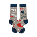 A pair of crew socks in grey and navy blue. One sock says 'Yes, I'm a Nurse', the other says 'No, I don't wanna look at it'.  They feature small white flowers and red heart designs.