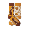 A pair of crew socks with a fun breakfast design. One sock features crispy brown bacon, the other shows sunny-side up eggs.  The main colors are mustard yellow and brown.