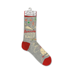 A pair of gray socks with a red toe, heel, and cuff. The socks have a pattern of Christmas trees, presents, and snowflakes. The words 