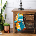 Lifestyle photo showing the Macaroni & Cheese socks casually draped over a wooden drawer. [lf]