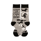 Pair of grey crew socks with black cuffs, heels, and toes, featuring white and black dogs and "SORRY I'M LATE! I SAW A DOG" text.