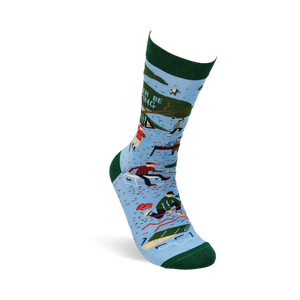 Single light blue crew sock with dark green trim. Design shows camping scenes, trees, a person chopping wood, and partial text 'R BE ING'.