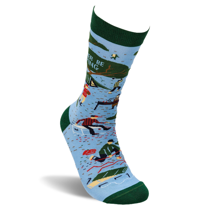 Single light blue crew sock with dark green trim. Design shows camping scenes, trees, a person chopping wood, and partial text 'R BE ING'.