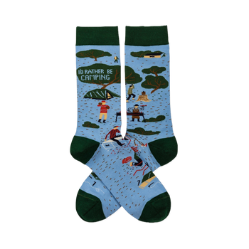 Pair of light blue crew socks with dark green trim. Features 'I'D RATHER BE CAMPING' text, trees, tents, and campers.
